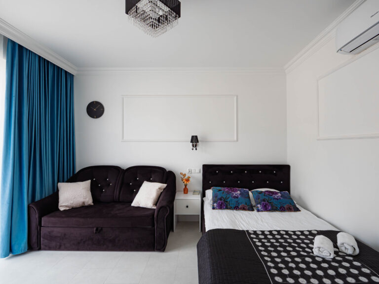 Elegancki apartament z podwójnym łóżkiem, sofą i niebieskimi zasłonami